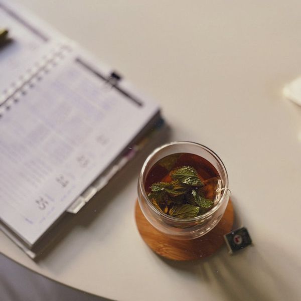 A neat desk with a planner, a cup of tea, and a plant.